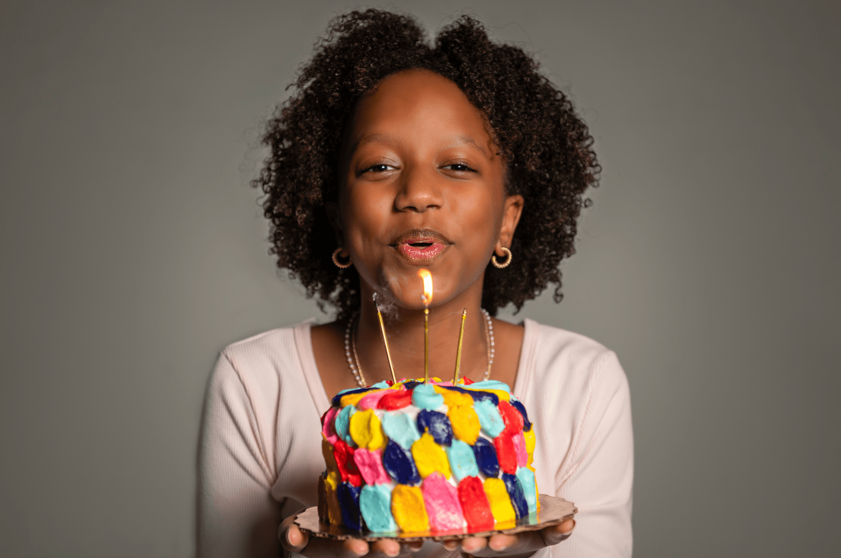 Payton, founder of Baked By Pay, blowing out candles on one of her hand-decorated cakes
